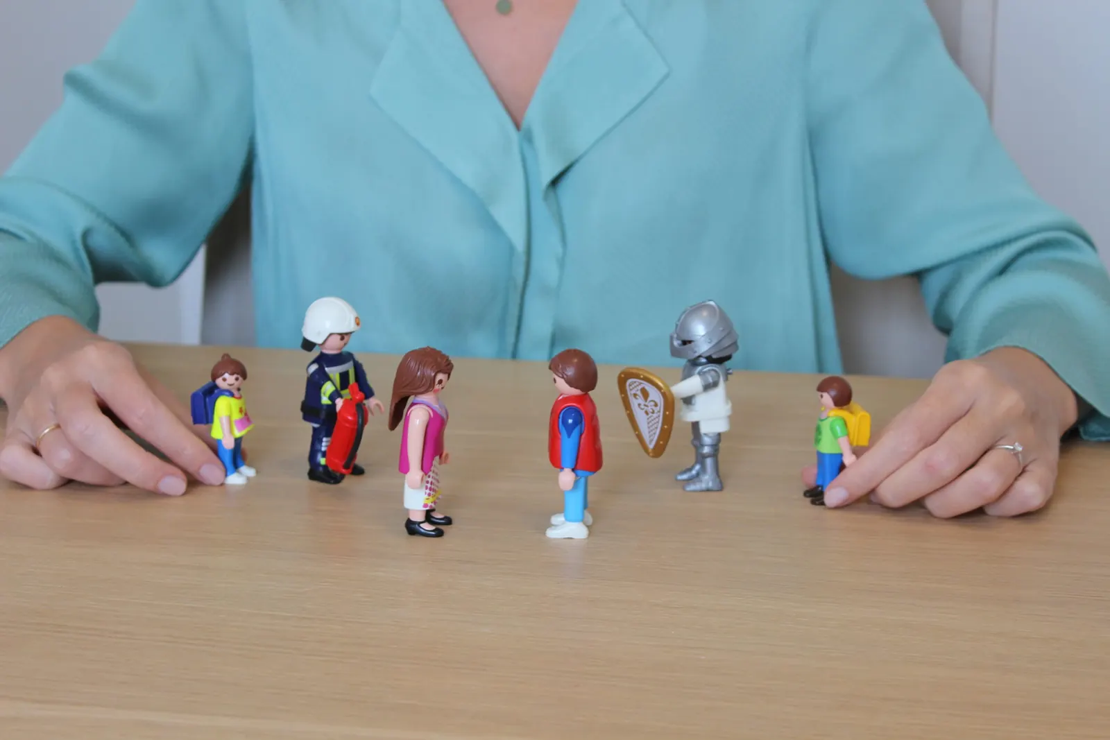Manos colocando figuras de Playmobil enfrentadas sobre la mesa